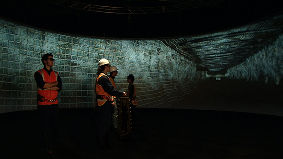 Miners standing in the centre of the AVIE 3D visualisation system, lookg at a projection of an underground mine.