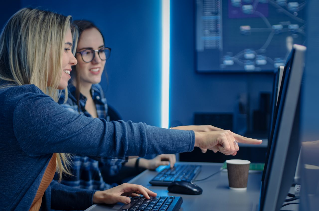 Two Female IT Programers Working on Desktop Computer in Data Center System Control Room. Team of Young Professionals In Software and Hardware Development, Doing Coding
