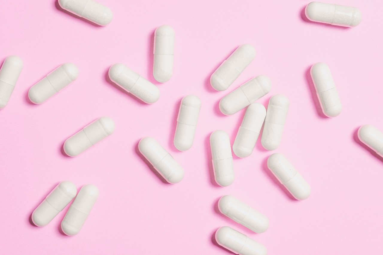 White pills on pink background