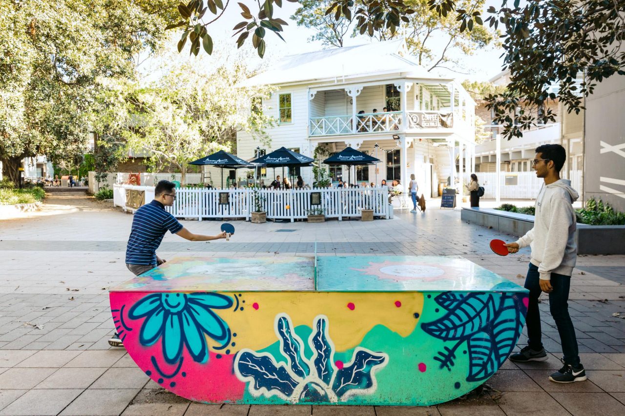 Students playing table tennis outdoors on campus