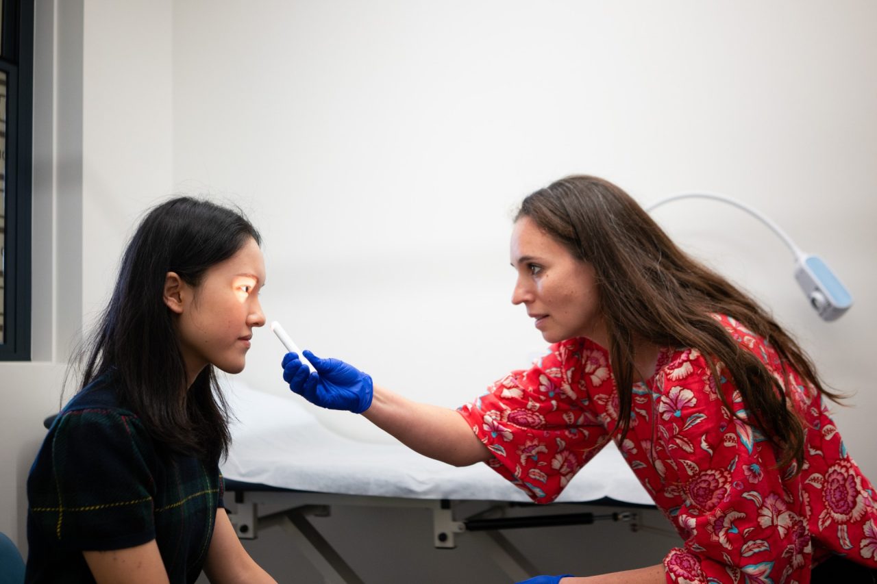 UNSW Health Service doctor is performing an eye exam on a student