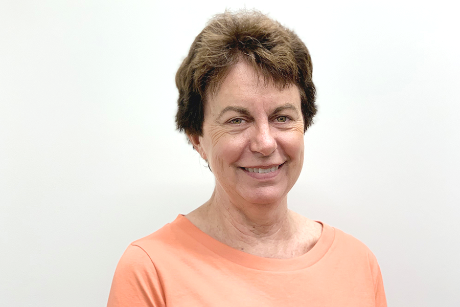 Dr. Judith Salmon in a peach-colored top, smiling gently in front of a plain white wall.