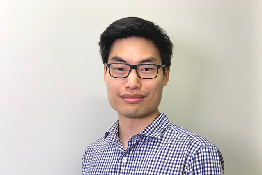 Dr. Jonathan Lim with short black hair and glasses wearing a checkered button-up shirt, standing in front of a plain light background with a calm, confident expression.