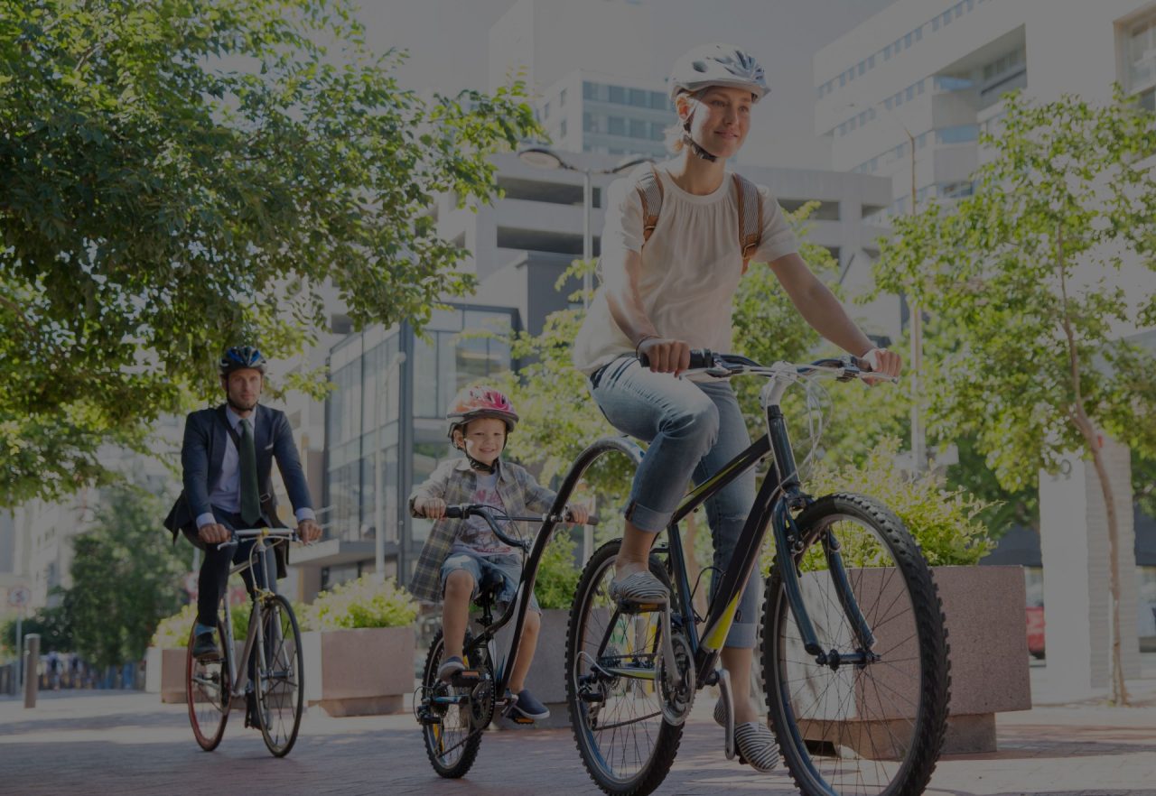 Mother and son in helmets riding tandem bicycle in urban park