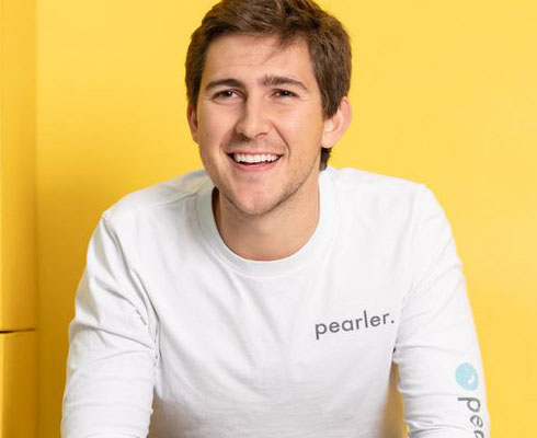 Kurt Walkom smiles in a pearler shirt against a yellow background